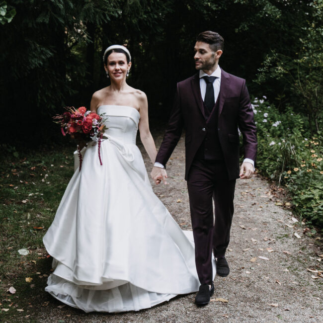 Brautpaar geht Hände haltend durch den Park des Schloss Mühlbach